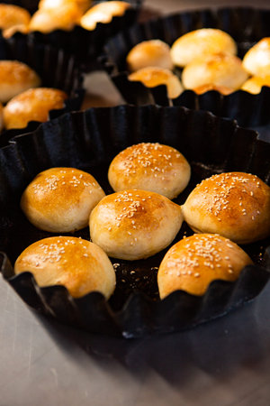Baked buns with sesame seeds on a baking sheet.