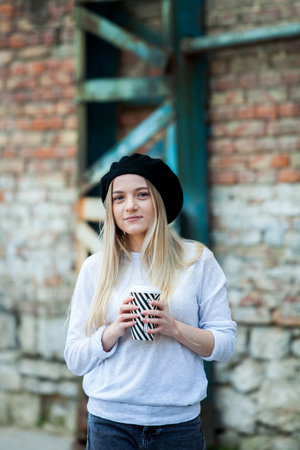 Portrait of a beautiful girl in a hat with a cup of coffeeの写真素材