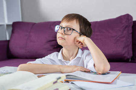 Portrait of a cute little boy with glasses studying at home.の写真素材
