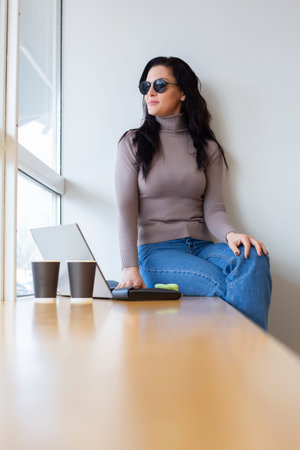 Portrait of a young woman using laptop while sitting at table in office