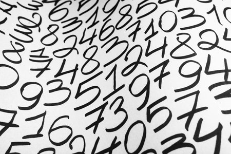 Black and white handwritten numbers on a white sheet of paper. Abstract background.の写真素材