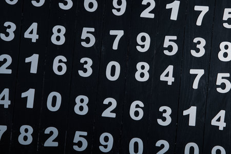 Background of numbers on a black wooden wall. Selective focus. Toned.の写真素材