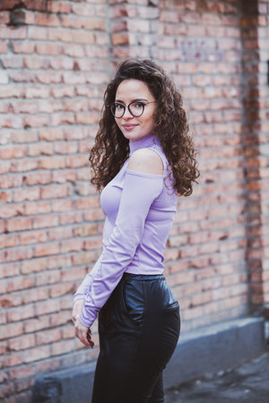young beautiful long curly hair hipster woman posing in the city streetsの写真素材