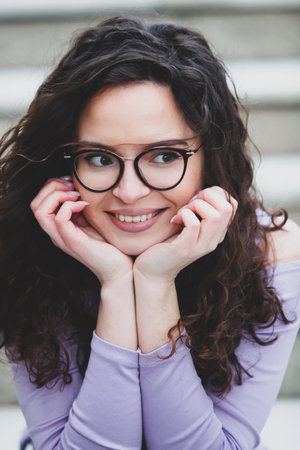 portrait of a beautiful young woman with long curly hair and glassesの写真素材