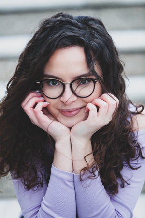 portrait of a beautiful young brunette woman in glasses with curly hairの写真素材