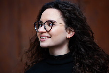 Portrait of a beautiful young woman with long curly hair and glasses