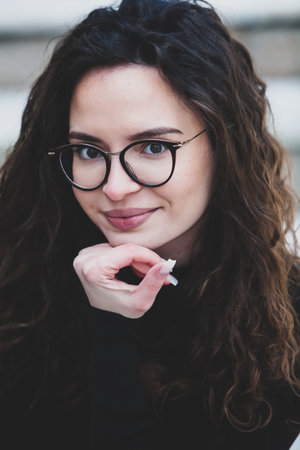 Portrait of a beautiful young woman with long curly hair and glasses