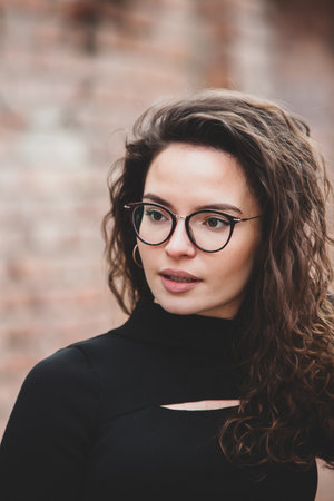 Portrait of a beautiful young woman with curly hair and glasses.の写真素材