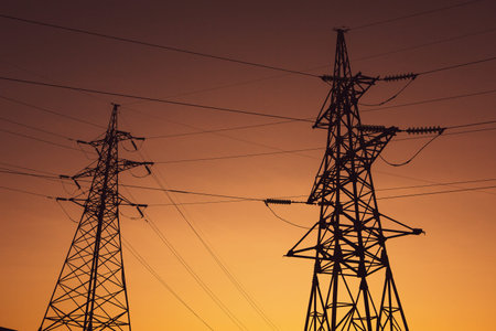 High voltage power lines and high voltage pylons at sunset.