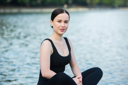 Portrait of a beautiful young woman sitting on the shore of a lake