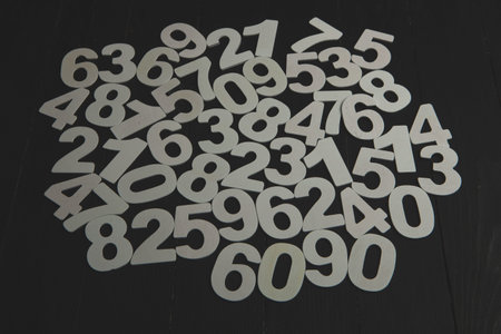Numbers on a black wooden background. Numbers are laid out in a circle.