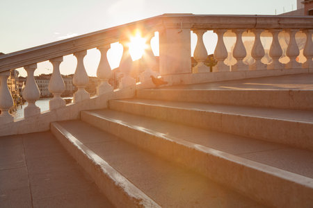 Stone stairs in the city park at sunset. Sun rays shining through the window.