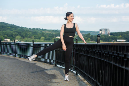 Beautiful young woman doing stretching exercise on the bridge in the city