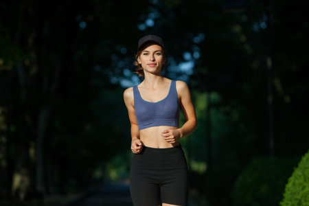 Running woman jogging in city park at beautiful summer day. Sport fitness model caucasian ethnicity training outdoor.の写真素材