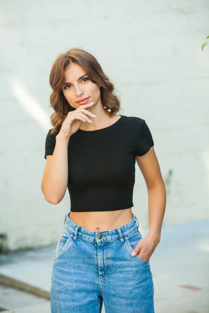 Portrait of a beautiful young woman in black top and blue jeans