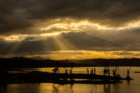 Silhouette of the port at sunset with rays of light.の写真素材