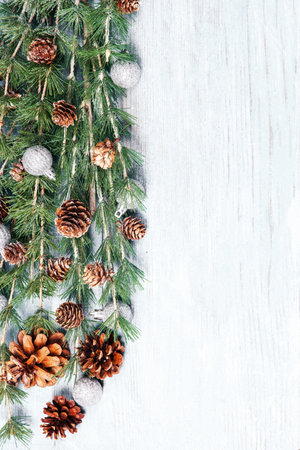 Christmas background with fir branches, cones and snowflakes on wooden backgroundの写真素材
