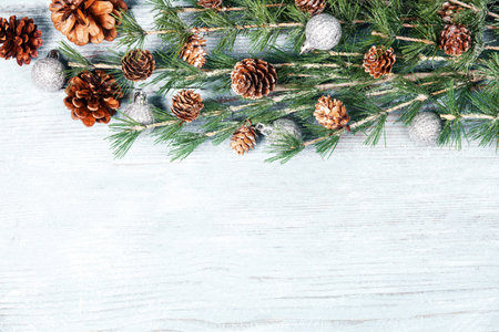Christmas background with fir branches, cones and decorations on white wooden boardの写真素材