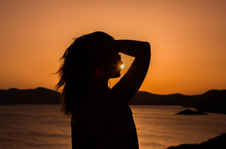 Silhouette of a young woman in a swimsuit at sunsetの写真素材