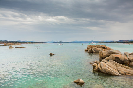 Tropical beach with rocks, turquoise water and cloudy skyの写真素材