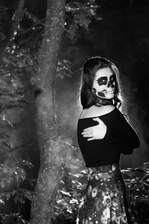 Portrait of a beautiful young woman with skull makeup in the forestの写真素材
