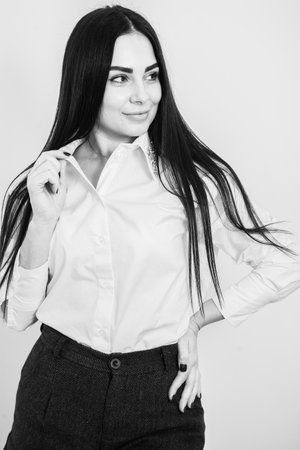 business woman with long brunette hair in white shirt and black skirt on grey backgroundの写真素材