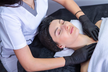 Young beautiful woman in a beauty salon getting a facial massage by a beautician