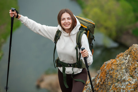 Young woman hiking in the mountains with a backpack and trekking poles.の写真素材