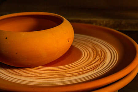 Freshly made clay mugs, pots and bowls drying up on wooden shelves in pottery workshop. Handmade ceramics manufacture. Different clay pots in workshop.の写真素材