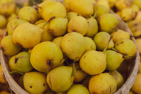 Ripe yellow pears in a wooden bowl on a wooden tableの写真素材