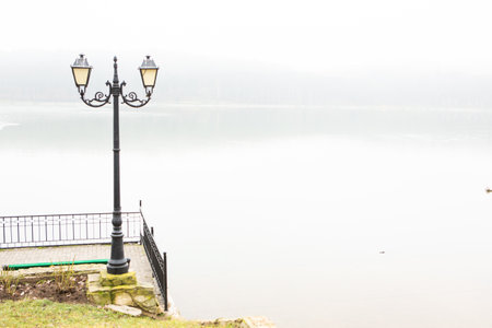Lantern on the bank of the lake in foggy day.Photo of the capital of the Republic of Moldova, Chisinau during the winter fog.の写真素材