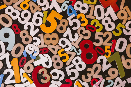 Colorful wooden numbers on blackboard background. Close-up.の写真素材