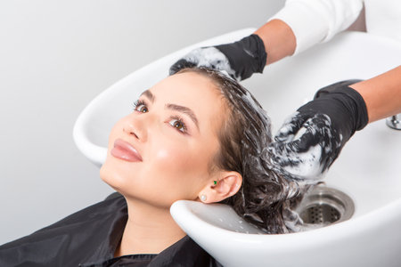 Hairdresser washing hair of young beautiful woman in beauty salonの写真素材