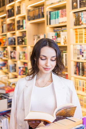 Young woman reading a book in the library. Education and leisure concept.
