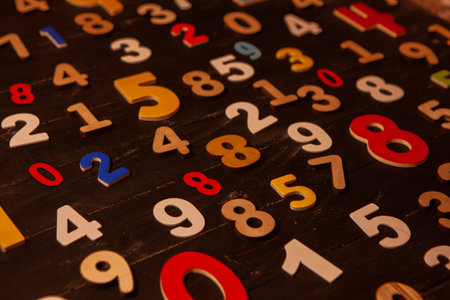 Colorful wooden numbers on a dark wooden background. Education concept.の写真素材