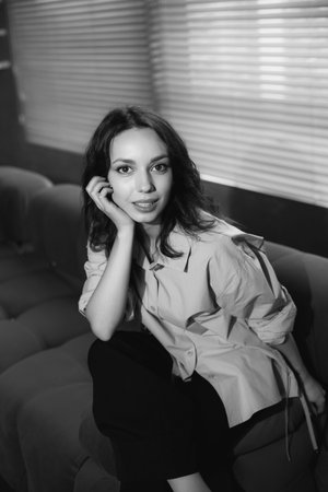 Black and white portrait of a beautiful young woman sitting on a sofa