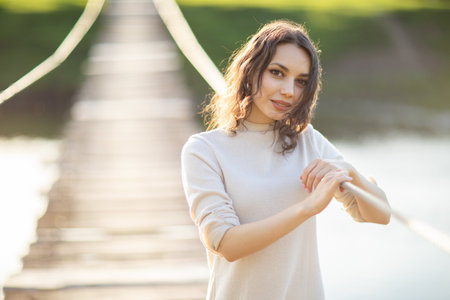 Portrait of a beautiful young brunette woman standing on the wooden bridgeの写真素材