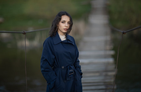 Portrait of a beautiful brunette girl in a blue trench coatの写真素材