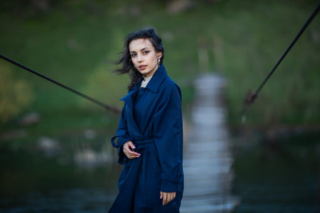 Portrait of a beautiful girl in a blue coat on the background of the riverの写真素材