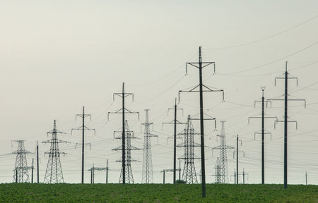 Electricity pylons in the field with green grass and blue sky
