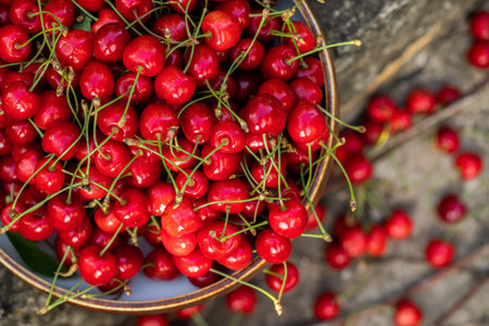 Ripe red cherries in a bowl on a wooden background.