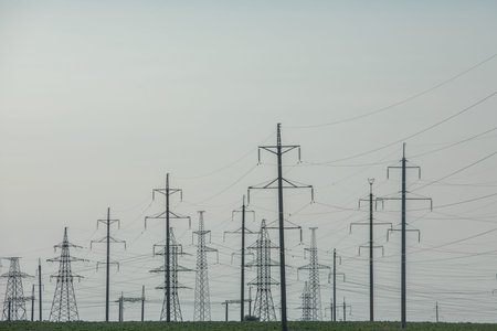 Electricity pylons in the field with blue sky background.