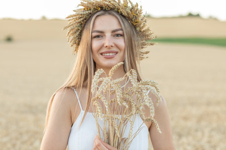 Beautiful girl in a wreath of wheat on a wheat fieldの写真素材
