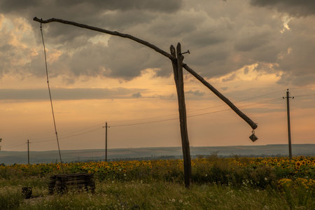 Sunflower field at sunset with a cloudy sky and a windmill. Beautiful landscape with beautiful rural...