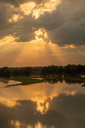 Sunset over a lake in the countryside in summer with dramatic clouds. Beautiful landscape with...