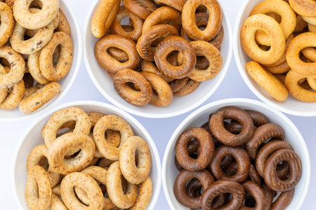 Bowls with a variety of bagels on a white background.