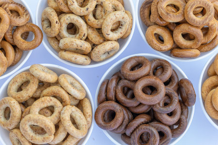 Bowls with different types of bagels on white background.