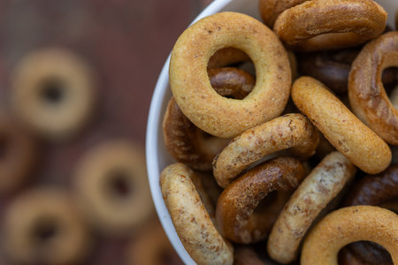 Freshly baked mini bagels on a dark background. Top view. Pretzels in the form of a ring close-up. Small bread circle biscuit. Bowls with different types of bagels..の写真素材