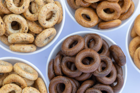 Bowls with different types of bagels on a white background