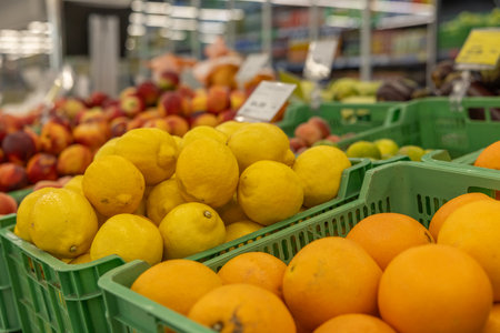 Oranges and lemons in a green box on a supermarket shelfの写真素材